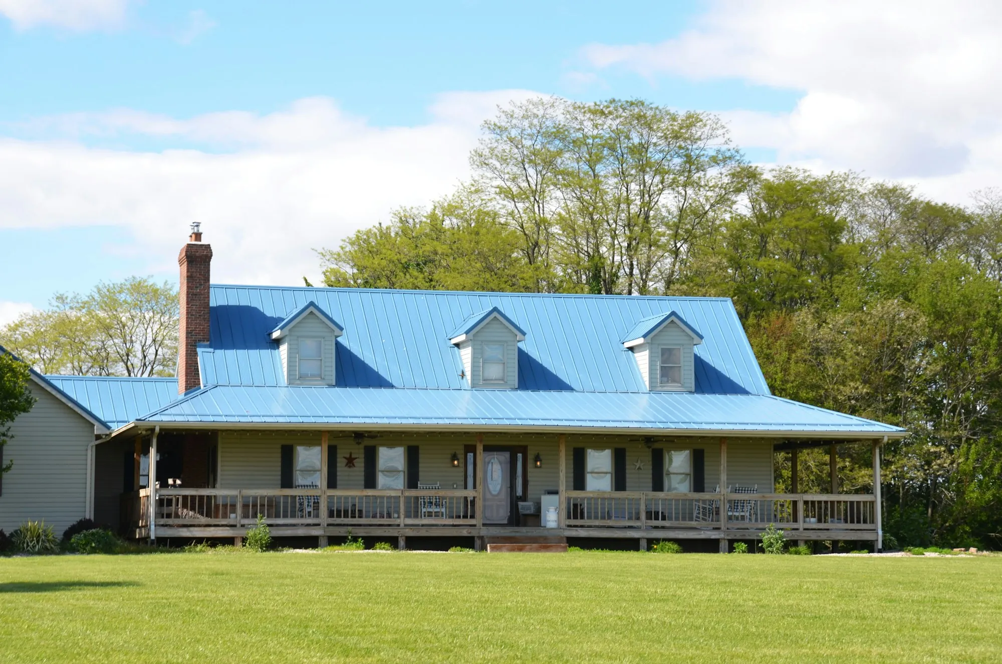 Ranch-style home with a blue metal roof and long front porch