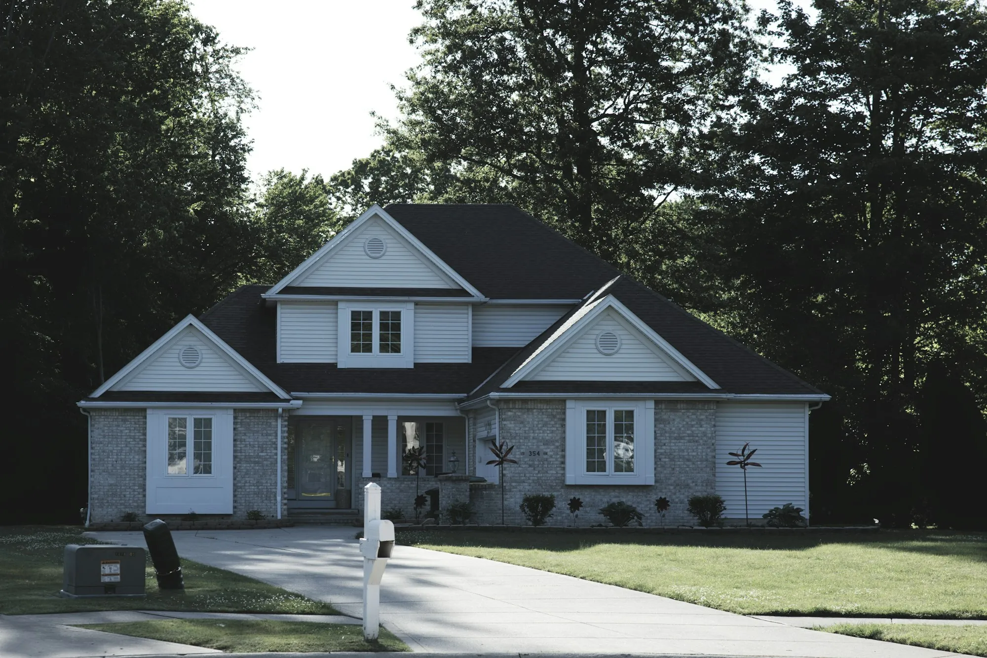 Gray and white two-story home with a stone front and dark roof